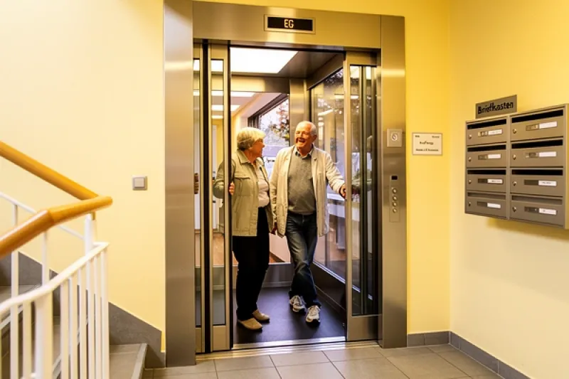 Älteres Paar steigt in einen Aufzug in einem Mehrfamilienhaus