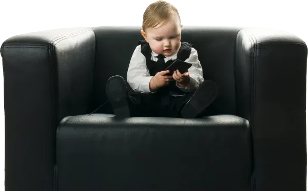 Kind sitzt im Chefsessel und bedient ein Mobiltelefon