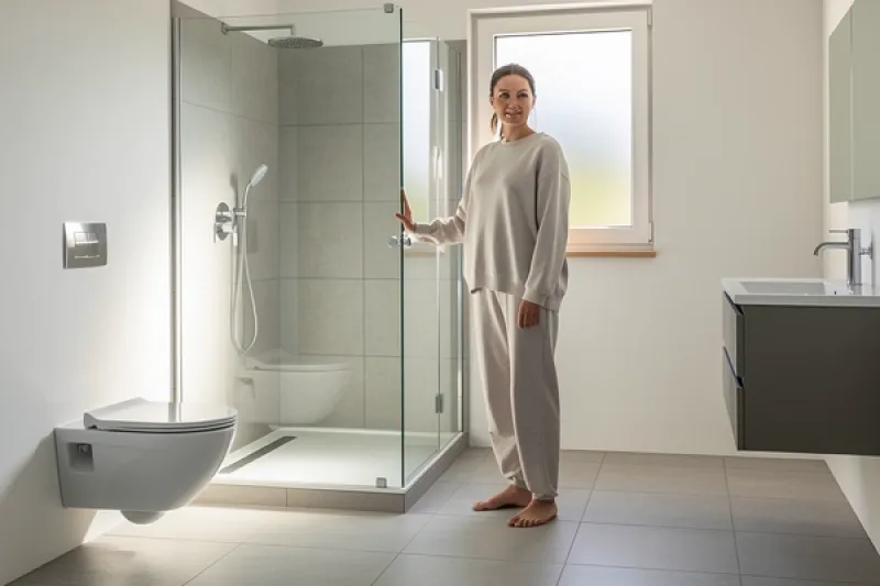 Frau steht im Badezimmer vor ihrer Dusche