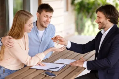 Makler übergibt Schlüssel an ein junges Paar